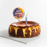 GRUB Singapore whole baked Basque burnt cheesecake with a caramelised top and a lit candle.
