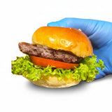 GRUB Singapore beef cheeseburger slider with lettuce, tomato, and onion on a brioche bun held by a gloved hand.