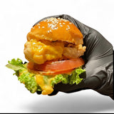 GRUB Singapore cheeseburger slider with sesame seed bun, lettuce, tomato, and cheese sauce, held in a black glove.