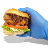 GRUB Singapore blue gloved hand holding a crispy chicken burger slider with lettuce, tomato, and caramelized onions.