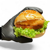 GRUB Singapore crispy fish burger slider with lettuce, tomato, and sauce on a sesame seed bun, held by a black gloved hand.