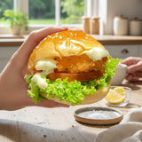 GRUB Singapore Crispy Fish Slider with lettuce, tomato, and tartar mayo on a mini brioche bun held in a black gloved hand.