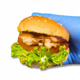 GRUB Singapore grilled chicken slider with lettuce, tomato, mayo, and teriyaki glaze on a brioche bun held by a blue gloved hand.