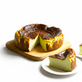 GRUB Singapore whole pandan burnt cheesecake with creamy centre and caramelised top, served on a wooden board with slices on plates.