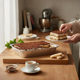 GRUB Singapore Tiramisu Tray with coffee soil, served in aluminum tray, a slice being lifted.